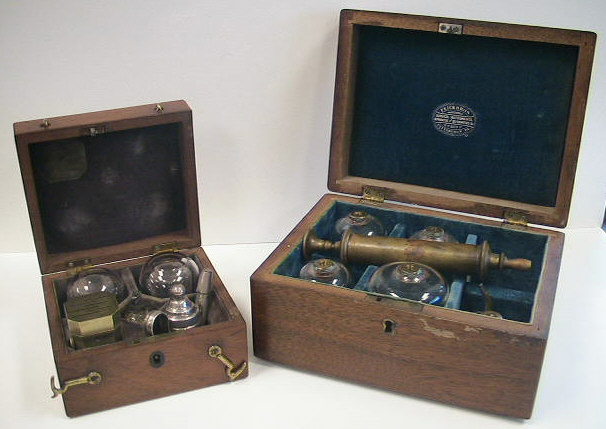 Savigny & Co. temple cupping set c.1840, London England.  Note the comparison above between a standard cupping set and the very diminutive size of the temple set.  The set contains a 6-bladed scarificator, two small cups, a silver teapot style burner for warming the glasses and a small cut glass bottle with alum for packing the cuts to stop the bleeding.