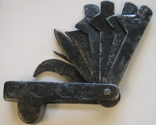Iron folding fleam with 4 fleam blades two bandage blades, a straight blade, and a leather punch.  Mexican in origin probably 1750-1775.