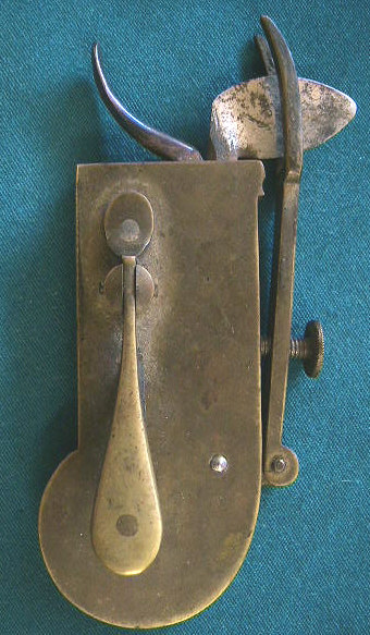 Common brass spring lancet in a red velvet lined case.  The lancet is unmarked.  This piece has a common form of depth gauge designed to raise and lower a bar that would rest against the patients skin prior to firing the piece.