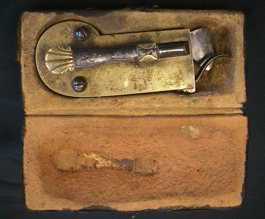 Very unusual brass cased Veterinary spring lancet.  Note that the blade retracts back behind the driver spring after firing.  The piece is decorated with a nice shell on the end of the release mechanism and on the back plate.  It is marked wiht the makers mark LOB.  Probably German in origin c.1800-1825.