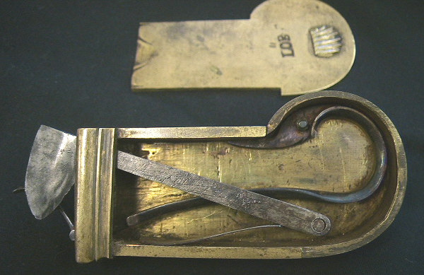 Very unusual brass cased Veterinary spring lancet.  Note that the blade retracts back behind the driver spring after firing.  The piece is decorated with a nice shell on the end of the release mechanism and on the back plate.  It is marked wiht the makers mark LOB.  Probably German in origin c.1800-1825.